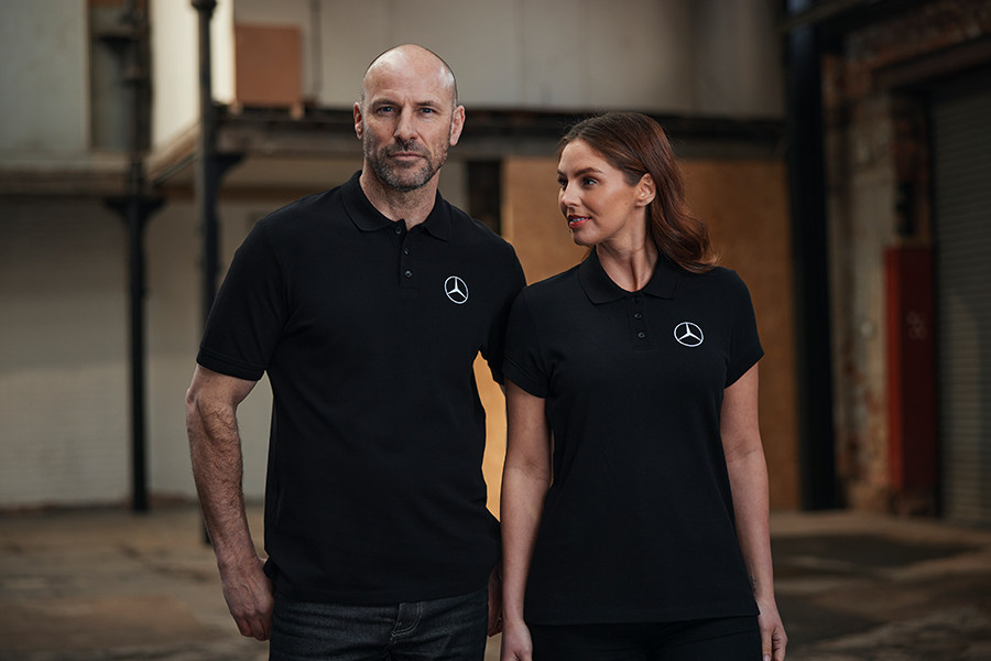 Two people wearing a black mercedes-benz branded polo shirts